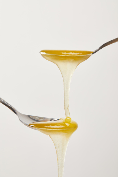 Nahaufnahme von Löffeln mit Honig auf weißem Hintergrund - Foto, Bild
