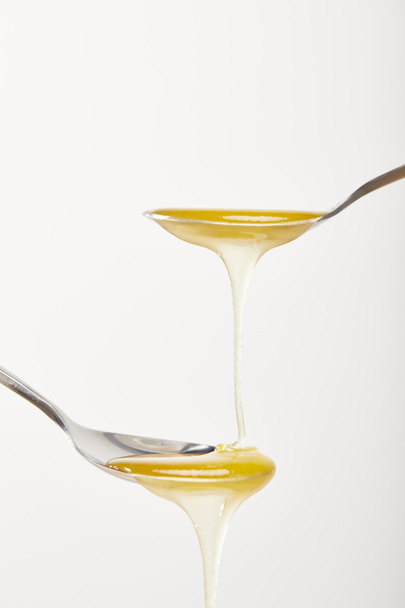 close up view of spoons with honey on white background - Foto, Imagem