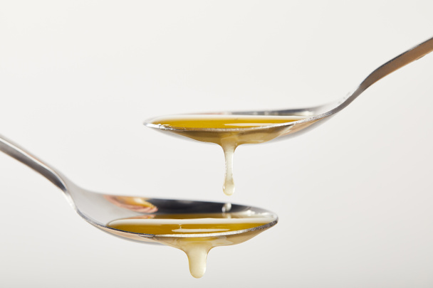 close up view of spoons with honey on white background - Foto, Imagem