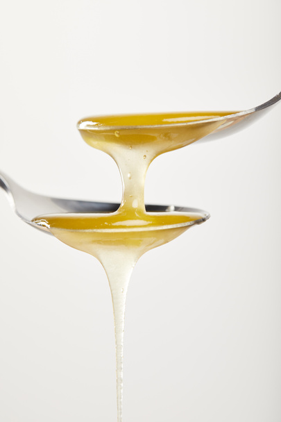 крупним планом вид ложок з медом на білому тлі
 - Фото, зображення