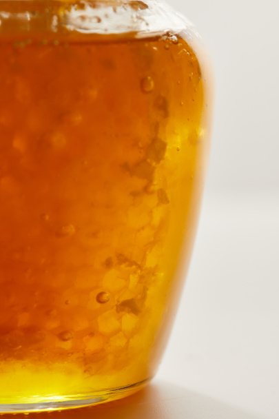κλείνω πάνω θέα από μέλι και κερί σε γυάλινο βάζο σε λευκό φόντο - Φωτογραφία, εικόνα