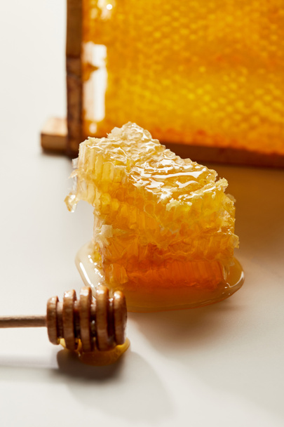 close up view of wooden honey deeper and stack of beeswax on white tabletop - Fotó, kép