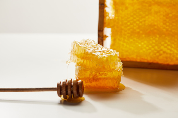 close up view of wooden honey deeper and stack of beeswax on white tabletop - Fotoğraf, Görsel