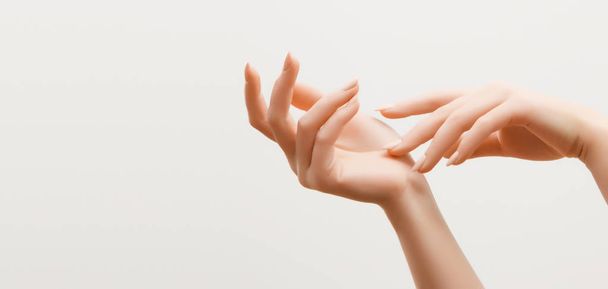 Крупным планом изображение рук красивой женщины со светло-розовым маникюром на ногтях. Уход за кожей рук, маникюр и косметические процедуры. Элегантные и изящные руки с тонкими изящными пальцами
 - Фото, изображение