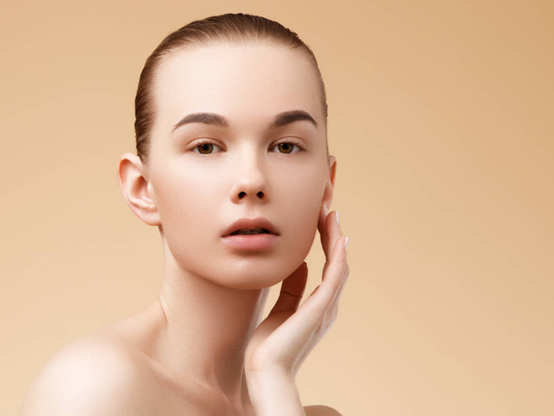 Skin care. Beauty Spa Woman with perfect skin Portrait. Beautiful Spa Girl. Proposing a product. Gestures for advertisement. Beige background - Foto, Imagem