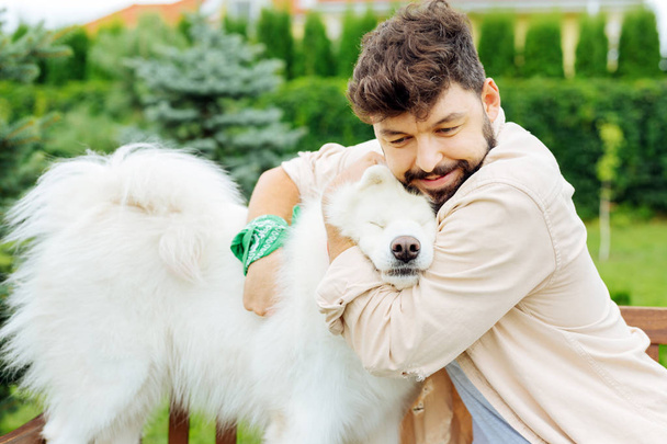 Liefdevolle eigenaar van schattige witte husky knuffelen zijn hond - Foto, afbeelding