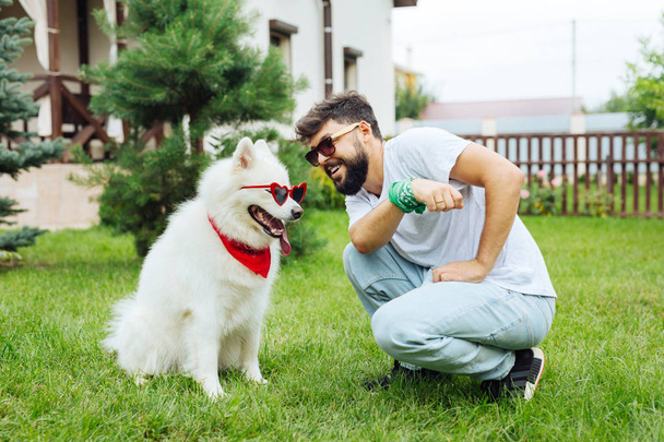 Creative man feeling funny while putting sunglasses on his husky - Foto, imagen