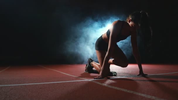 Kadın atlet karanlık bir arka plan üzerinde koyu arka plan üzerinde treadmill yastıkları arazi sprint çalıştırılmaya hazırlanıyor - Video, Çekim