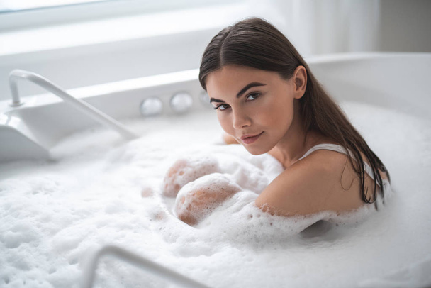 Calm woman resting in water with foam - Photo, image