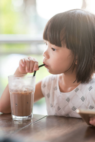 Chica asiática bebiendo chocolate helado en el café. Estilo de vida al aire libre luz natural
. - Foto, Imagen