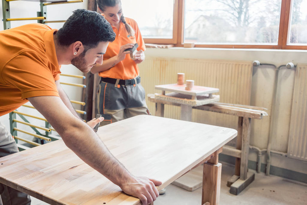 Equipa muitas vezes wo carpinteiros trabalhando em uma mesa
 - Foto, Imagem