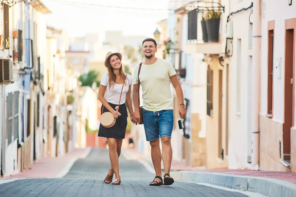 Young happy couple walking holding each others hand in old Spanish town. Stylish man and woman on vacations in Spain, Europe. Tourism and travelling concept. - Фото, изображение