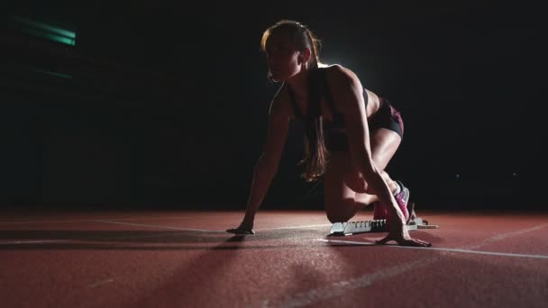 Sportlerin auf dunklem Hintergrund bereitet sich auf den Langlauf-Sprint von den Polstern auf dem Laufband auf dunklem Hintergrund vor - Filmmaterial, Video