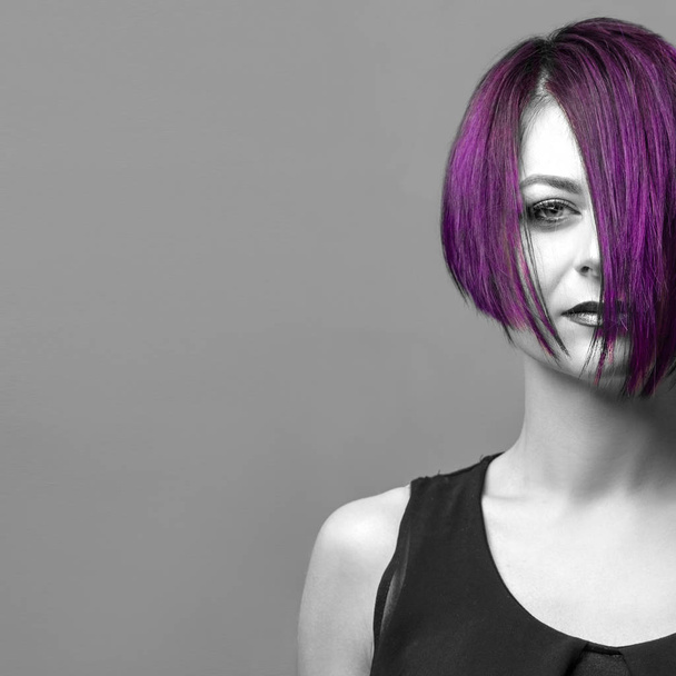 Fashion woman with purple short hair over gray background, copy space - Fotó, kép