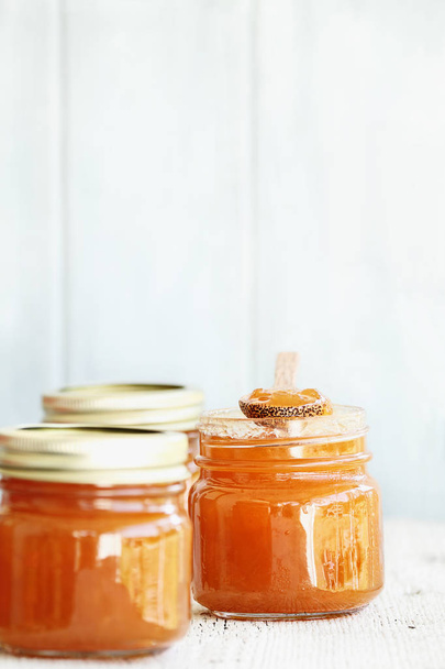 A row of mason jars full of homemade Cantaloupe Jam against a rustic background. Extreme shallow depth of field with selective focus on center jar. Image could also be used for peach jelly or a marmalde.  - Fotografie, Obrázek