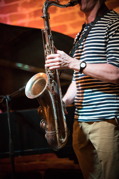 Un musicien anonyme en t-shirt rayé joue du saxophone dans un bar de jazz, performance live
 - Photo, image