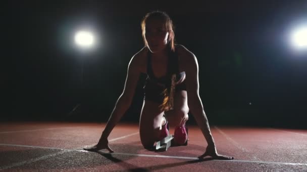 Female athlete on a dark background to run the sprint of the cross country pad on the treadmill on a dark background - Footage, Video