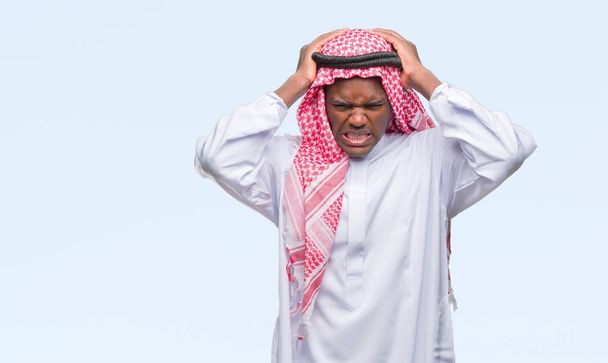 Jeune homme arabe africain portant keffiyeh traditionnelle sur fond isolé souffrant de maux de tête désespérés et stressés parce que la douleur et la migraine. Mains sur la tête
. - Photo, image