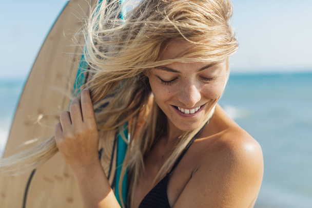Portrait of a pretty blonde woman surfer standing on beach. - Foto, Imagem