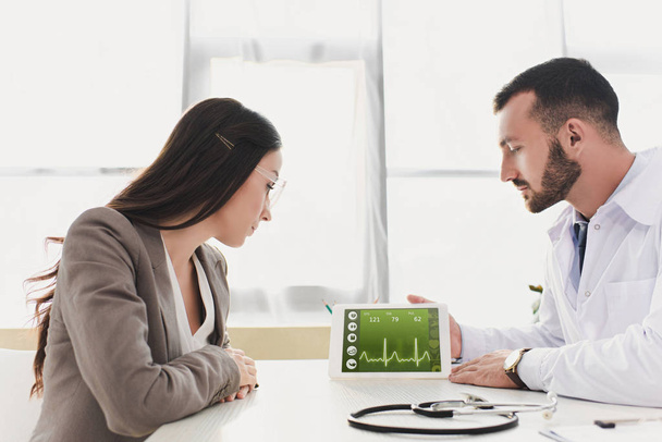 médico mostrando tablet paciente com aplicativo médico na clínica
 - Foto, Imagem
