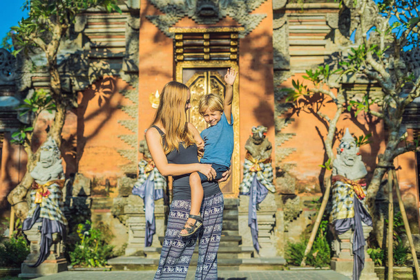 Mom holding son near Ubud palace in sunlight, Bali - Photo, image