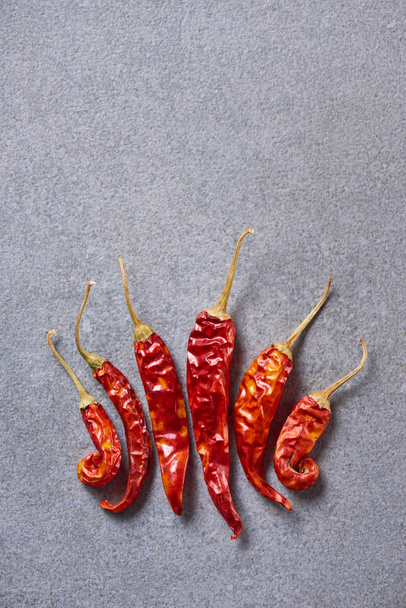 top view of red chili peppers arranged on grey tabletop - Zdjęcie, obraz