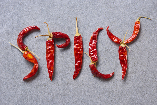 top view of dried chili peppers arranged in spicy lettering on grey tabletop - Photo, Image