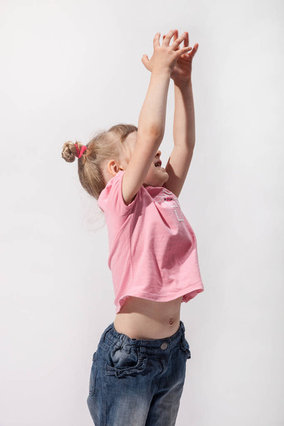 Active little girl catching something her hands, neutral background - Фото, изображение