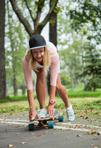 Happy girl skating on a longboard, natural background - 写真・画像