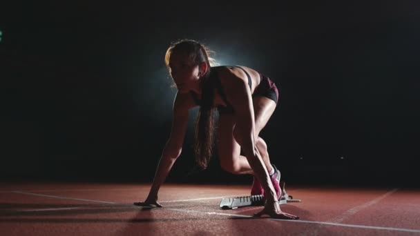 Професійна жінка-спортсмен на темному тлі, щоб бігати спринтом взуття в кросівках на треку стадіону на темному тлі
 - Кадри, відео