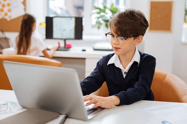 Smart boy using a laptop in a classroom - Photo, image