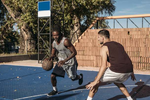Two handsome men playing basketball outdoors. - Photo, image