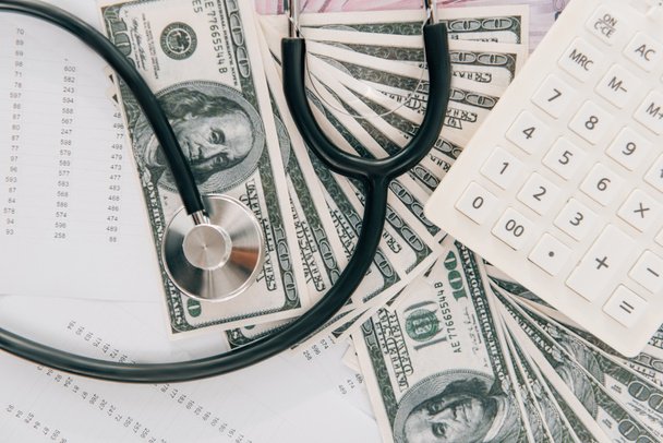 top view of stethoscope, dollar banknotes and calculator, health insurance concept - Photo, Image