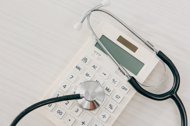 Widok z góry z stetoskop leżącego na biały kalkulator, pojęcie ubezpieczenia zdrowotnego - Zdjęcie, obraz