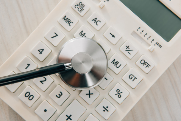 top view of stethoscope on white calculator, health insurance concept - Zdjęcie, obraz
