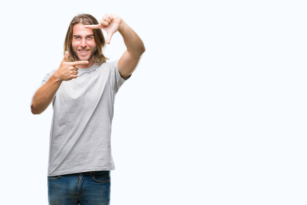 Young handsome man with long hair over isolated background smiling making frame with hands and fingers with happy face. Creativity and photography concept. - Φωτογραφία, εικόνα