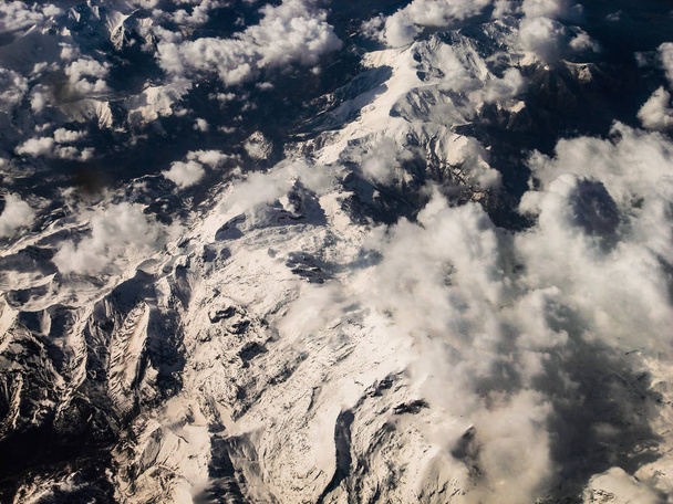 Snowy mountains among clouds aerial view - Фото, изображение