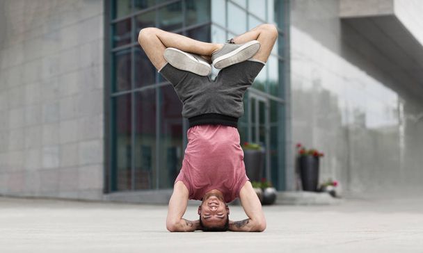 Профессиональный йог делает упражнения на голове на открытом воздухе
 - Фото, изображение