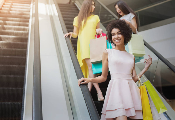 Gelukkig multiraciale meisjes op roltrap in winkelcentrum - Foto, afbeelding
