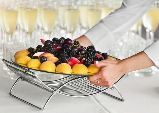 Waiter putting fruit tray on table at party - Photo, Image