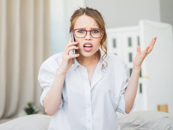 Portret van gefrustreerd jonge vrouw freelancer houden van mobiele telefoon en boos schreeuwen als ze niet het maken van online betaling of een probleem met de verbinding. - Foto, afbeelding