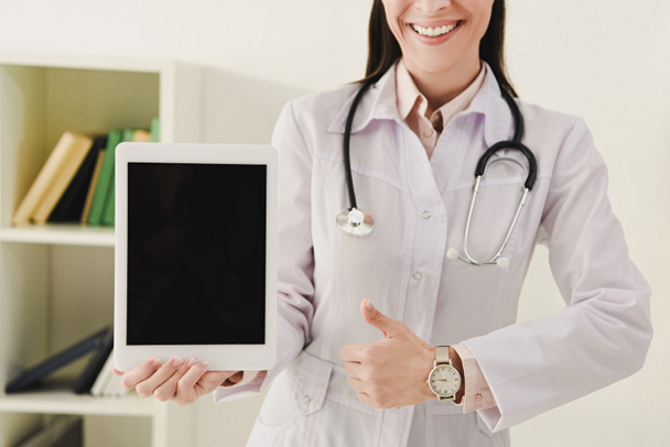 vista recortada del médico mostrando el pulgar hacia arriba y la presentación de la tableta digital con pantalla en blanco
 - Foto, Imagen