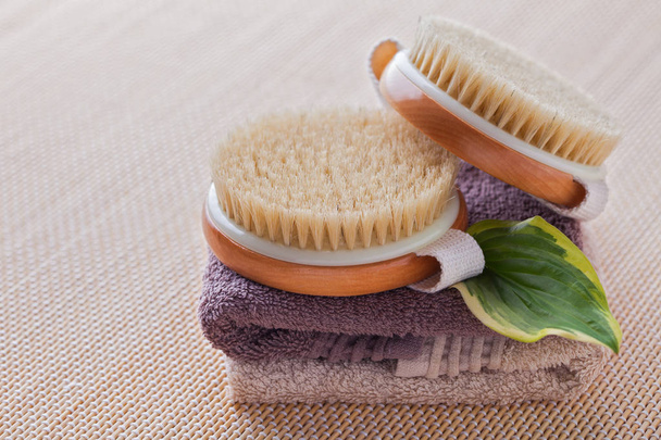 two brushes for dry body massage on towels and green leaf, beauty treatment  - Photo, Image