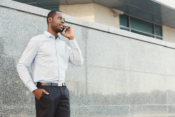 Портрет уверенного молодого чернокожего бизнесмена, разговаривающего по сотовому
  - Фото, изображение
