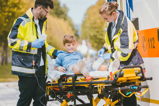 Sağlık görevlilerinin koyarak çocuk sedye üzerinde kazadan sonra yaralı. - Fotoğraf, Görsel