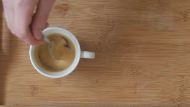Taza de café espresso caliente con crema, revolviendo a mano el café con una cuchara
 - Metraje, vídeo