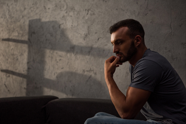 lonely pensive man sitting on sofa at home - Fotografie, Obrázek
