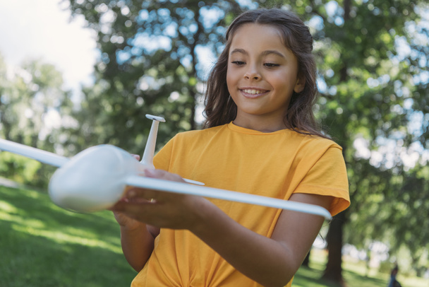 close-up view of cute smiling child holding toy plane model in park - Photo, Image