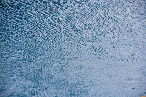 Vesi pieniä aaltoja ja sadepisaroita uima-altaalla sininen rakenne tausta
 - Valokuva, kuva