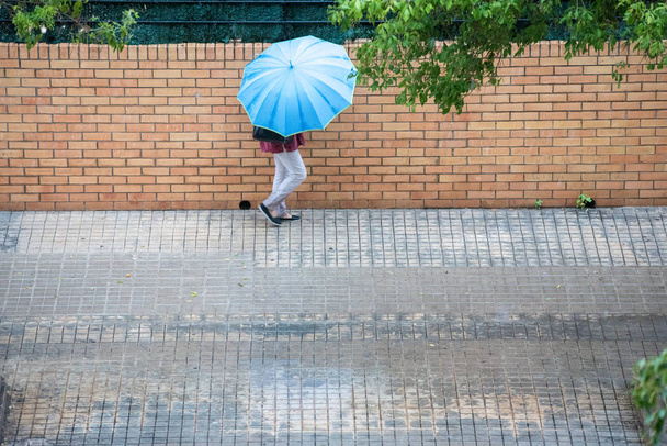 Γυναίκα με ομπρέλα τρέχει στους δρόμους, ενώ η βροχή πέφτει - Φωτογραφία, εικόνα